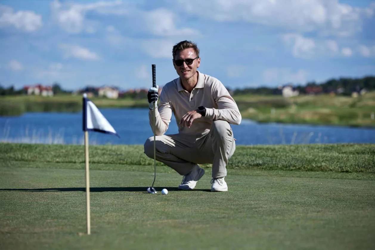male golfer crouching down aiming for hole